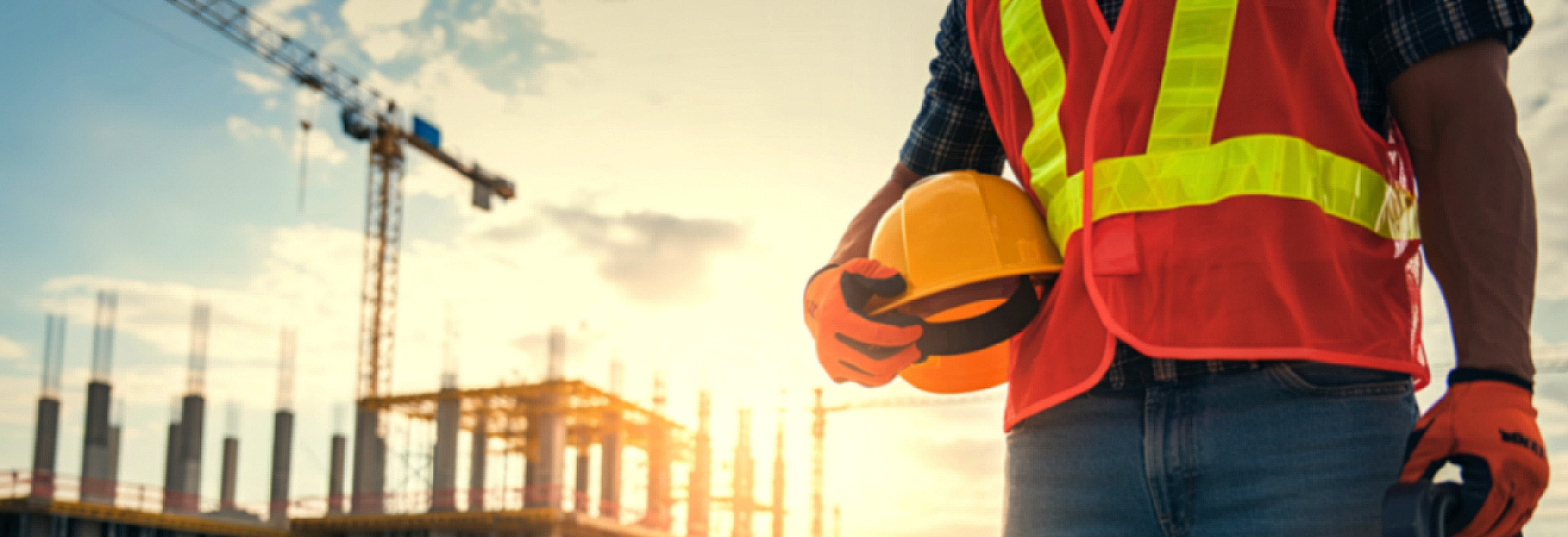 construction working standing in front of commercial project holding hard hat